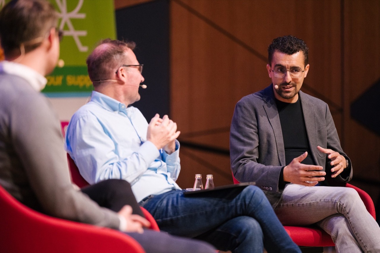 Panellists in red armchairs in conversation on stage